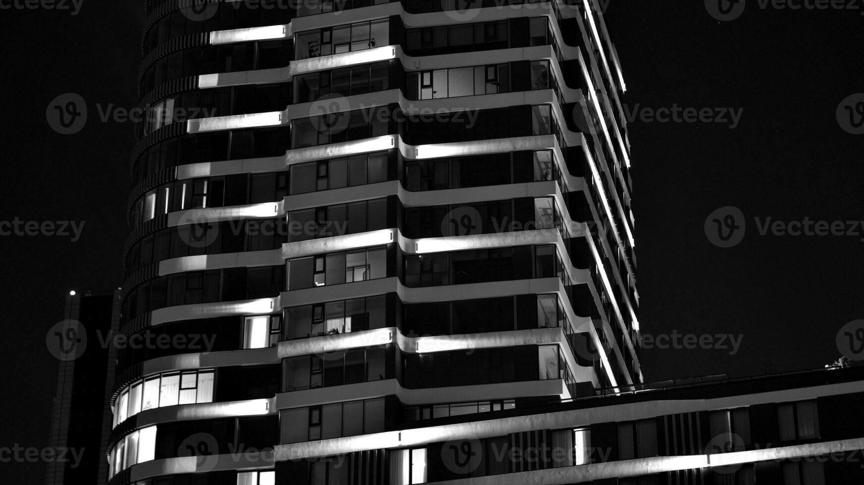 Pattern of office buildings windows illuminated at night. Glass architecture ,corporate building at night - business concept. Black and white. photo