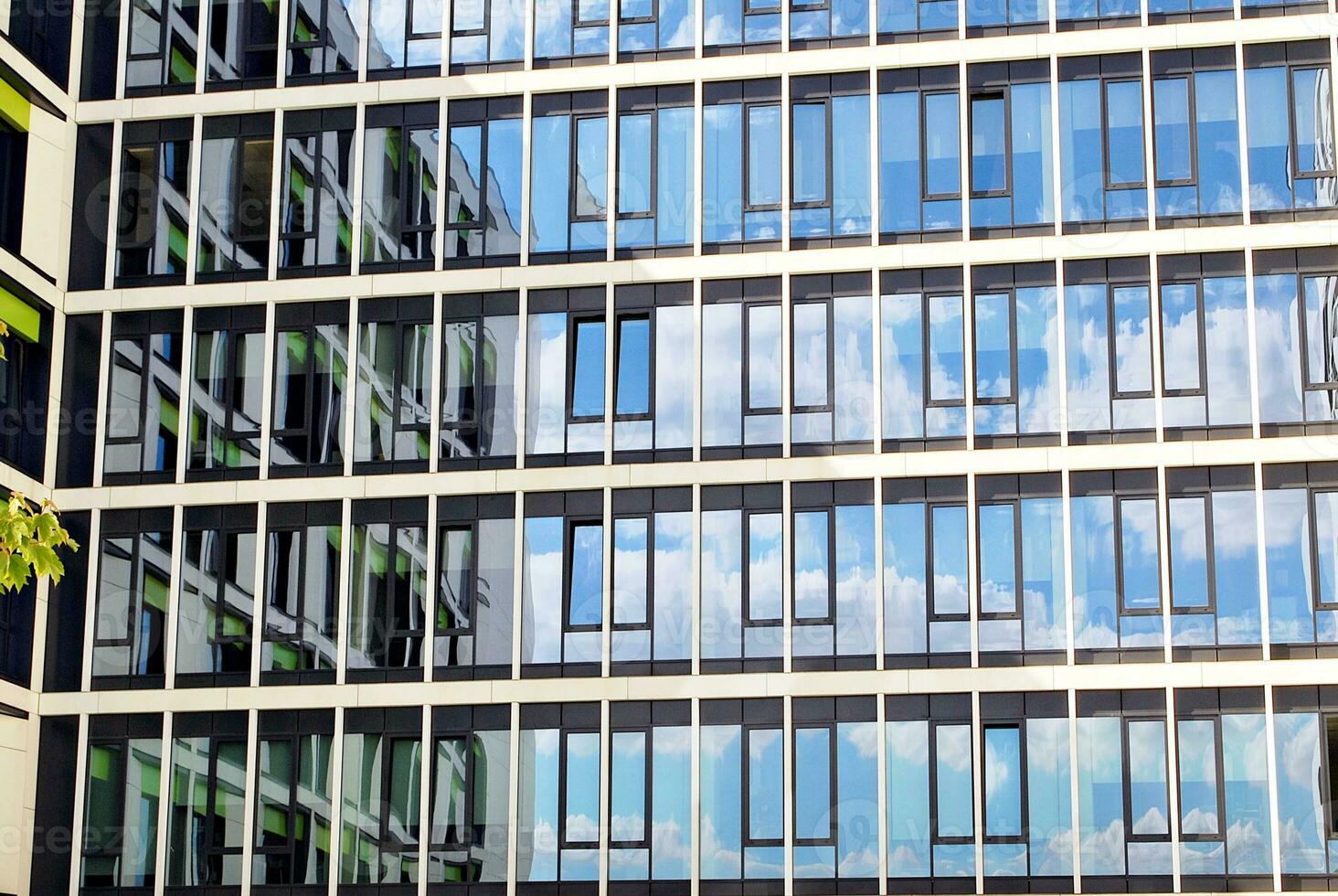 Abstract closeup of the glass-clad facade of a modern building covered in reflective plate glass. Architecture abstract background. Glass wall and facade detail. photo