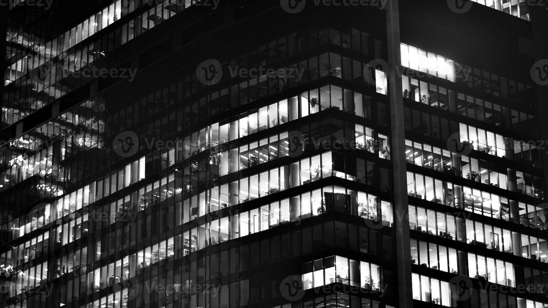 Pattern of office buildings windows illuminated at night. Glass architecture ,corporate building at night - business concept. Black and white. photo