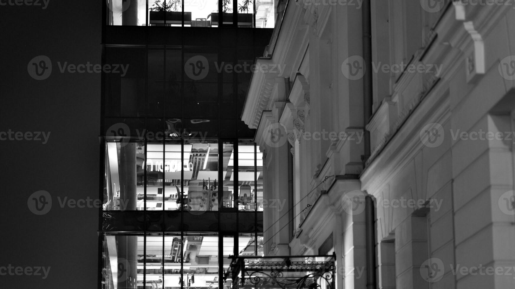 Pattern of office buildings windows illuminated at night. Glass architecture ,corporate building at night - business concept. Black and white. photo