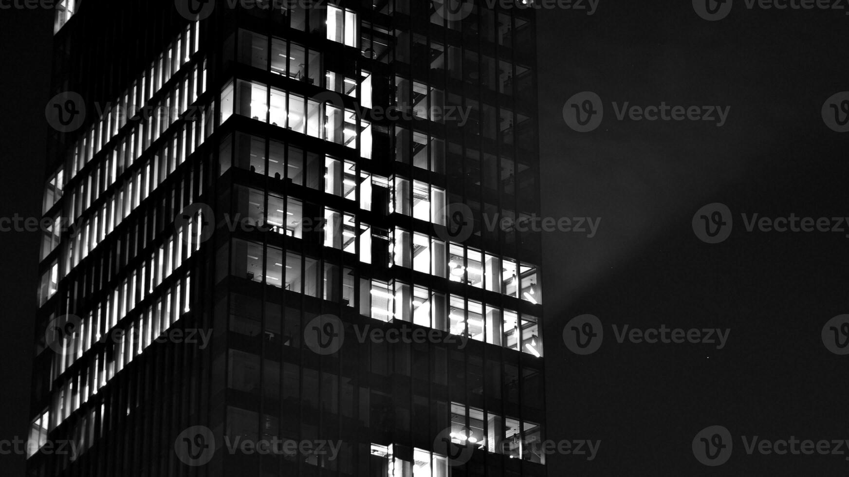 Pattern of office buildings windows illuminated at night. Glass architecture ,corporate building at night - business concept. Black and white. photo