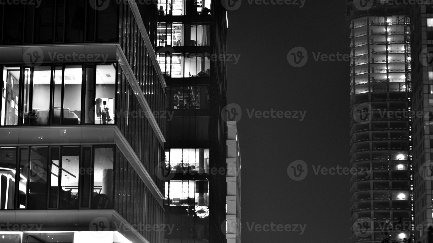 Pattern of office buildings windows illuminated at night. Glass architecture ,corporate building at night - business concept. Black and white. photo