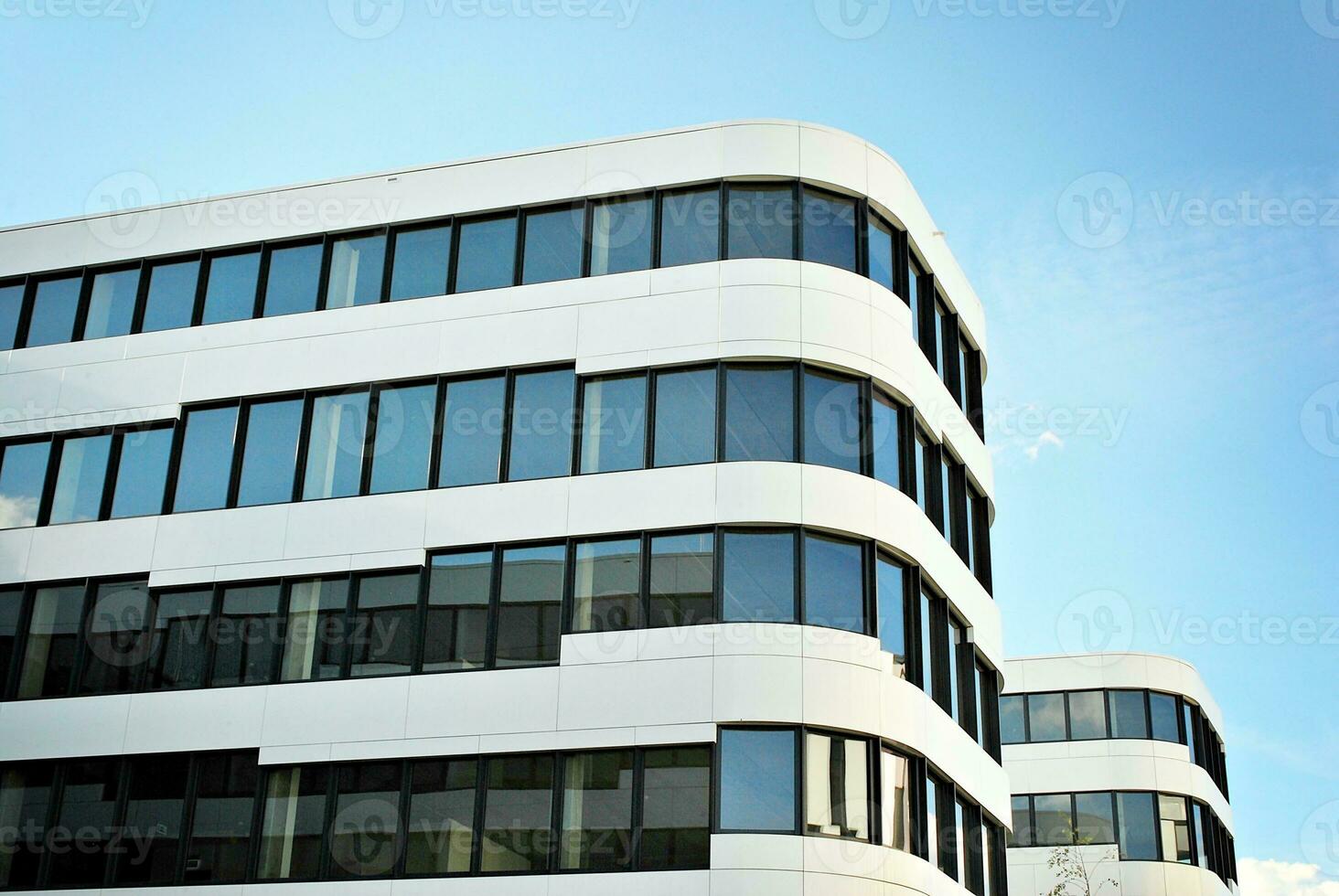 Abstract closeup of the glass-clad facade of a modern building covered in reflective plate glass. Architecture abstract background. Glass wall and facade detail. photo