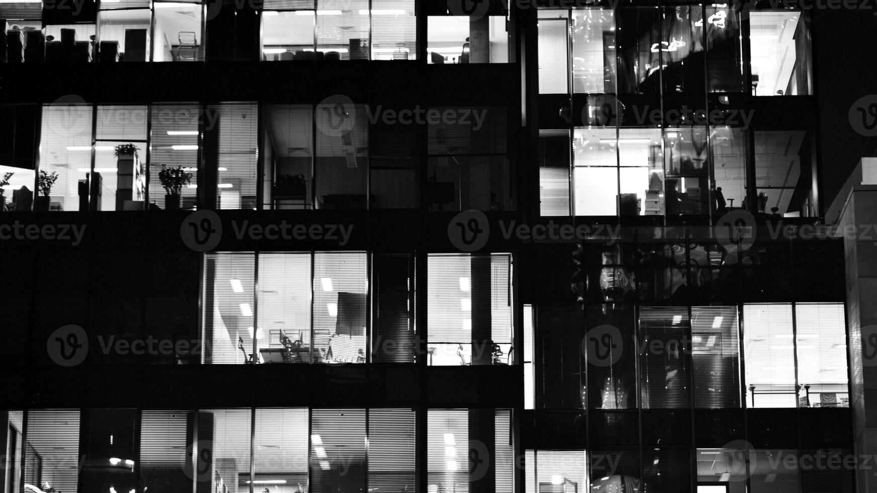 Pattern of office buildings windows illuminated at night. Glass architecture ,corporate building at night - business concept. Black and white. photo