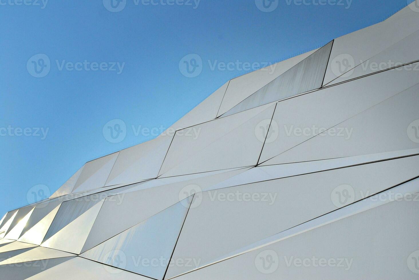 Abstract closeup of the glass-clad facade of a modern building covered in reflective plate glass. Architecture abstract background. Glass wall and facade detail. photo