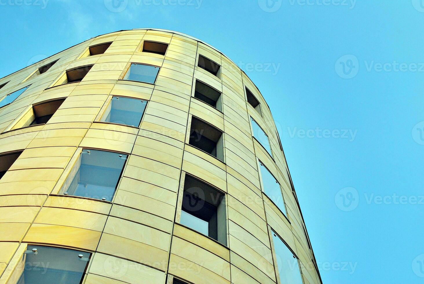 Abstract closeup of the glass-clad facade of a modern building covered in reflective plate glass. Architecture abstract background. Glass wall and facade detail. photo