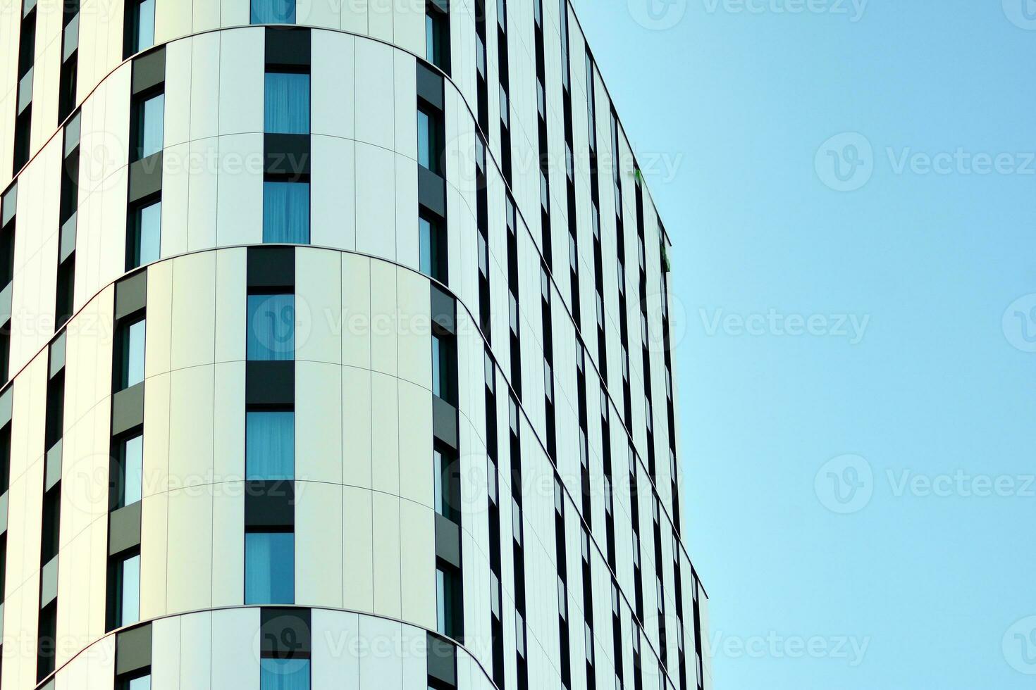 Abstract closeup of the glass-clad facade of a modern building covered in reflective plate glass. Architecture abstract background. Glass wall and facade detail. photo