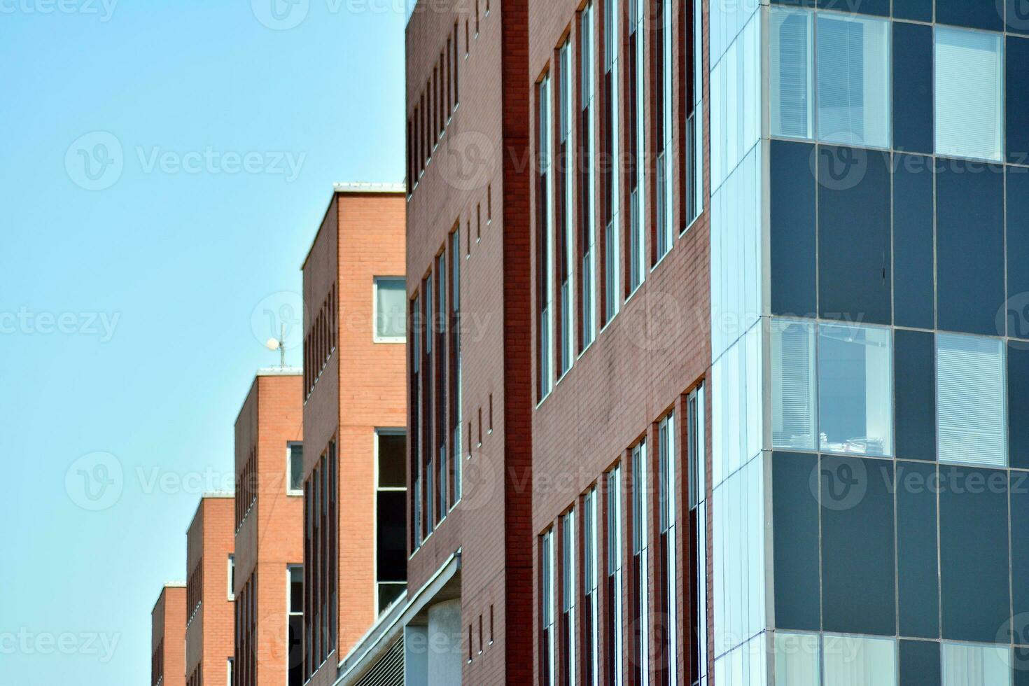 Abstract closeup of the glass-clad facade of a modern building covered in reflective plate glass. Architecture abstract background. Glass wall and facade detail. photo