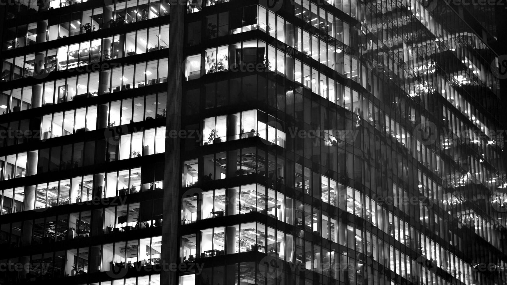 Pattern of office buildings windows illuminated at night. Glass architecture ,corporate building at night - business concept. Black and white. photo