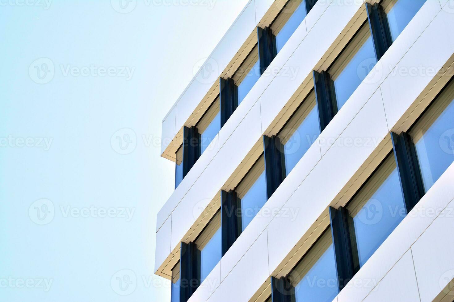 Abstract closeup of the glass-clad facade of a modern building covered in reflective plate glass. Architecture abstract background. Glass wall and facade detail. photo