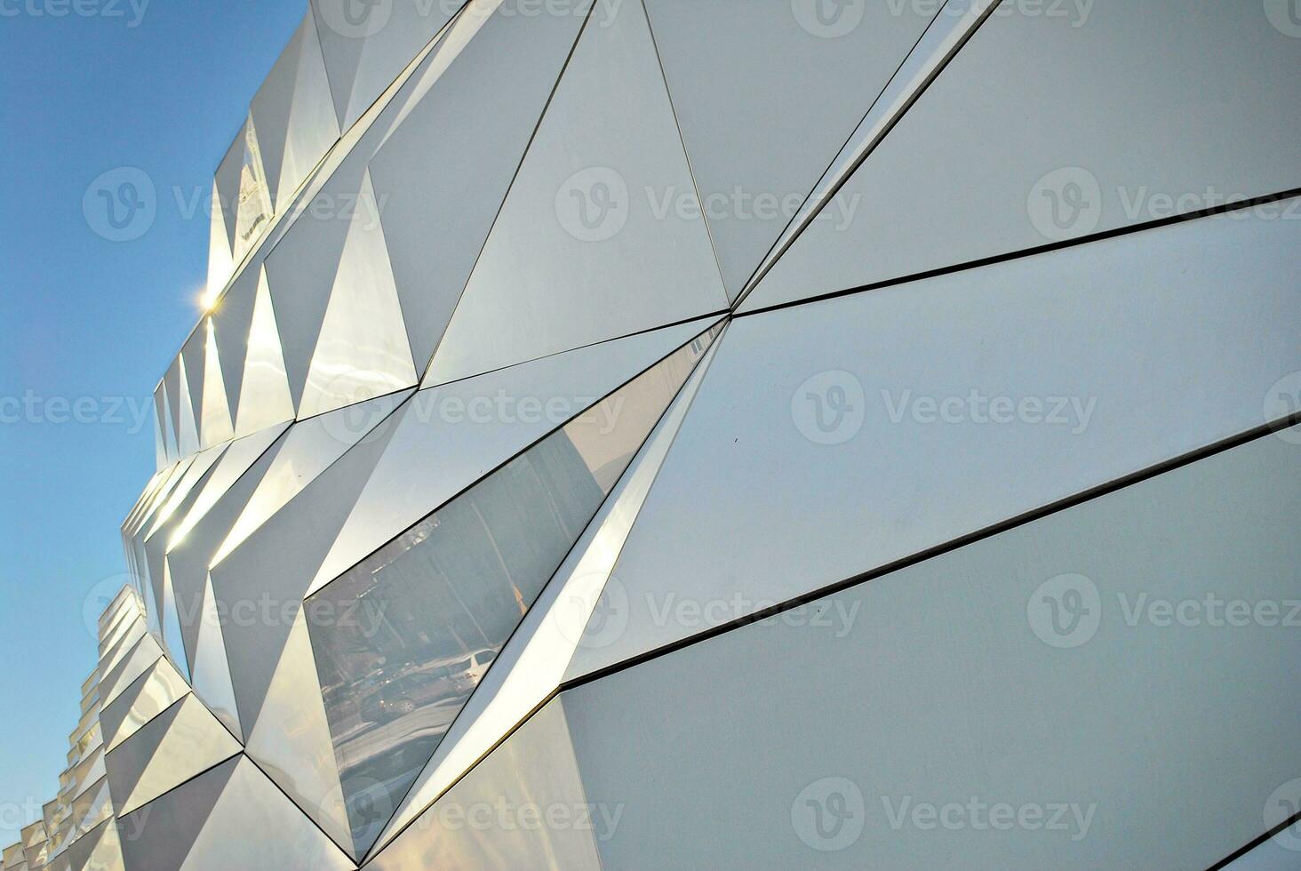 Abstract closeup of the glass-clad facade of a modern building covered in reflective plate glass. Architecture abstract background. Glass wall and facade detail. photo