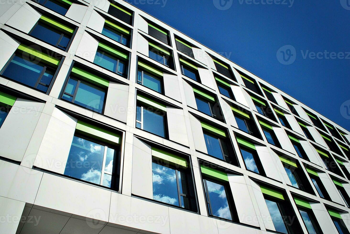 Abstract closeup of the glass-clad facade of a modern building covered in reflective plate glass. Architecture abstract background. Glass wall and facade detail. photo