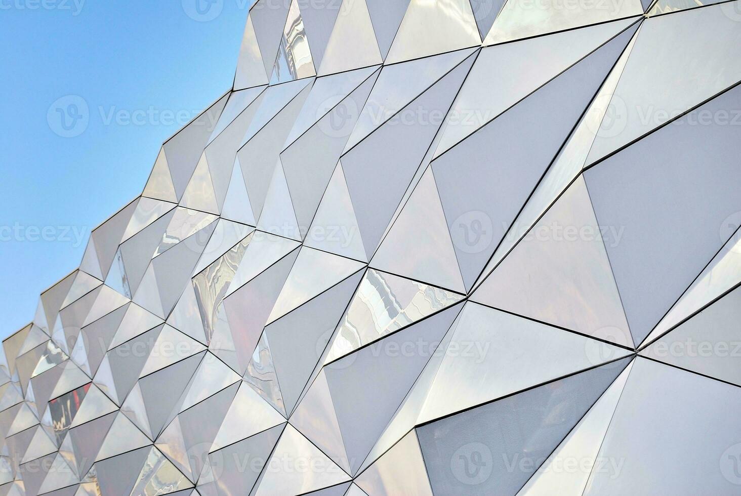 Abstract closeup of the glass-clad facade of a modern building covered in reflective plate glass. Architecture abstract background. Glass wall and facade detail. photo