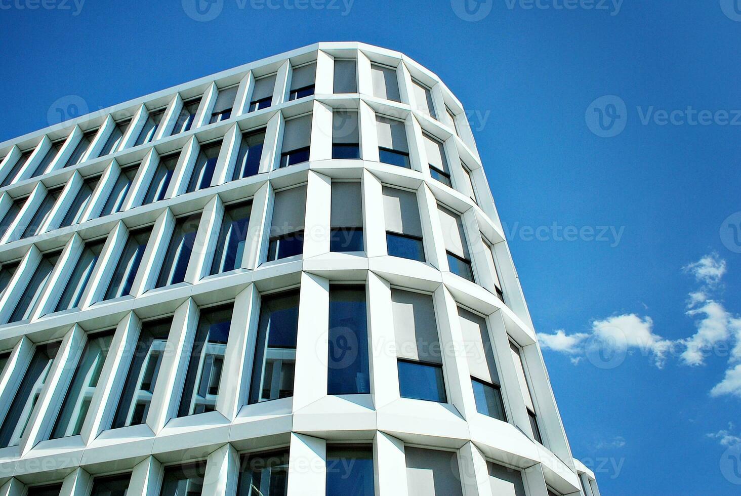 Abstract closeup of the glass-clad facade of a modern building covered in reflective plate glass. Architecture abstract background. Glass wall and facade detail. photo