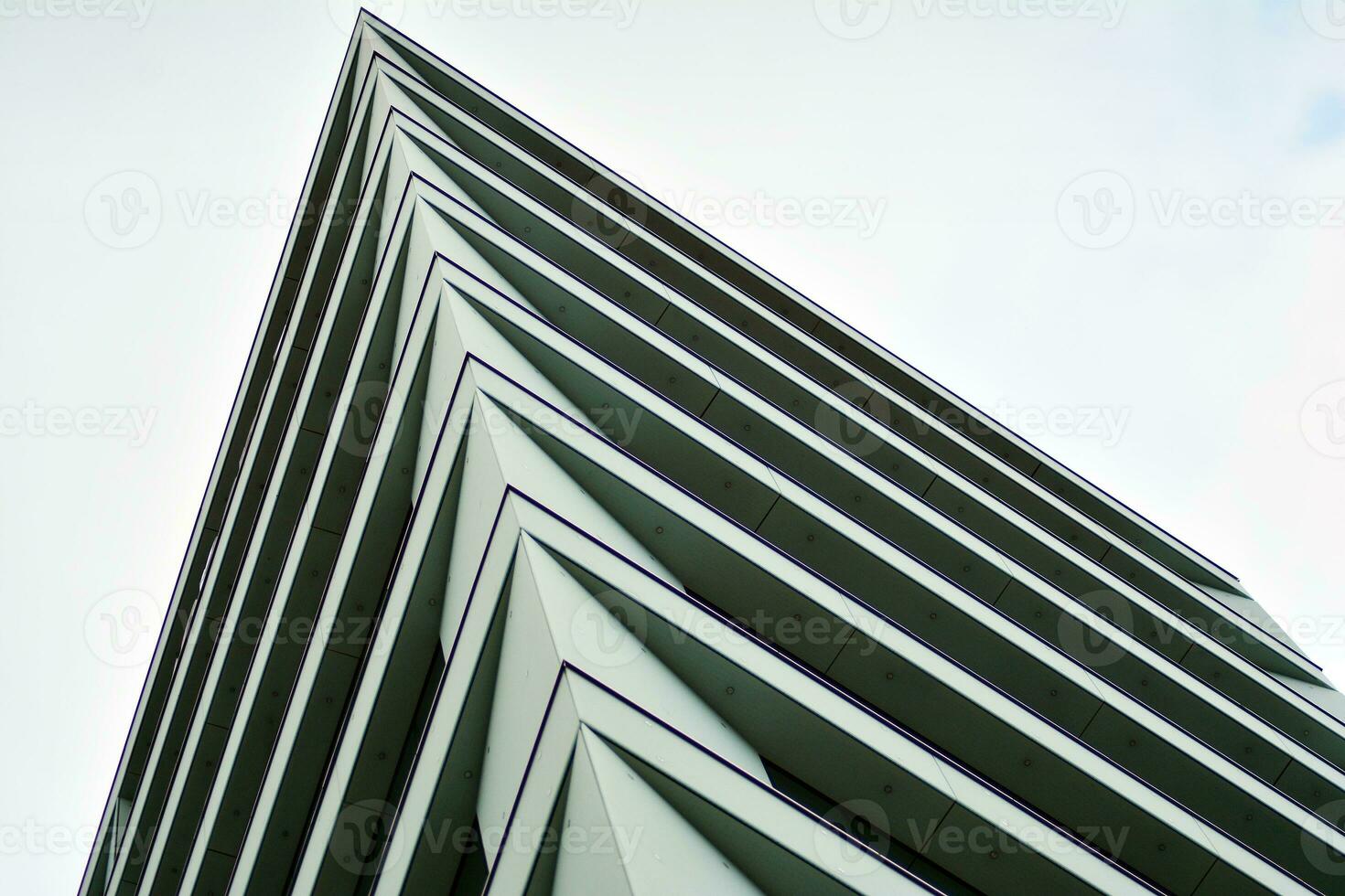 Abstract closeup of the glass-clad facade of a modern building covered in reflective plate glass. Architecture abstract background. Glass wall and facade detail. photo