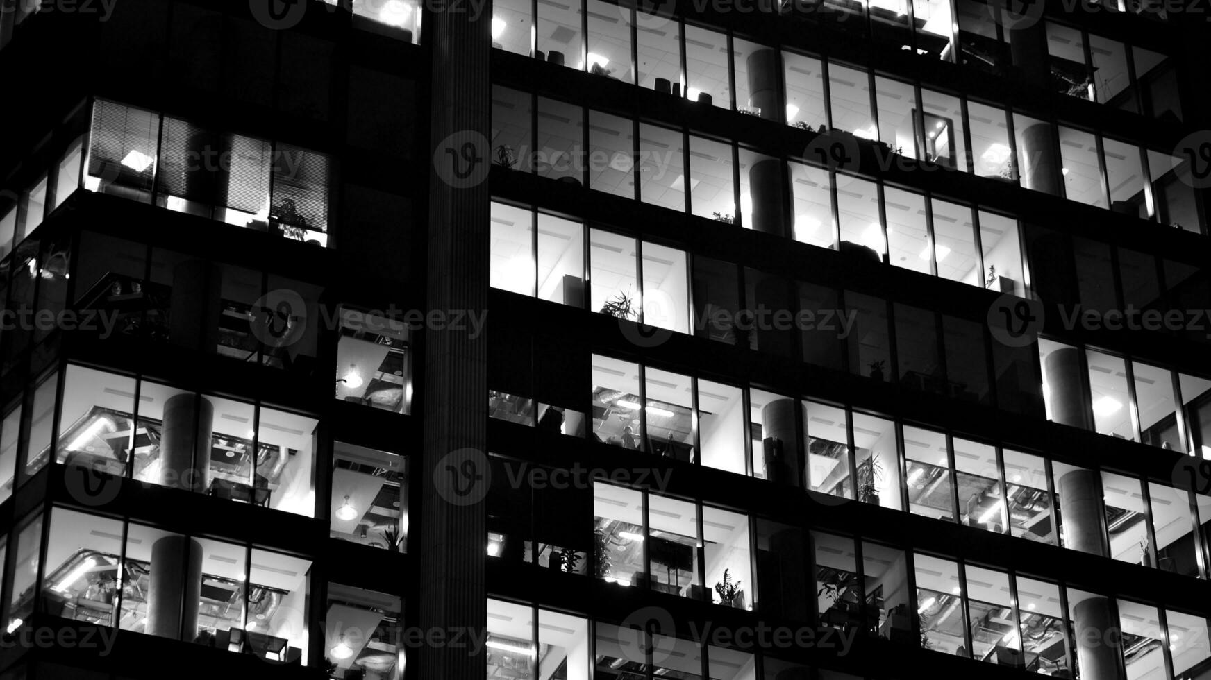 Pattern of office buildings windows illuminated at night. Glass architecture ,corporate building at night - business concept. Black and white. photo