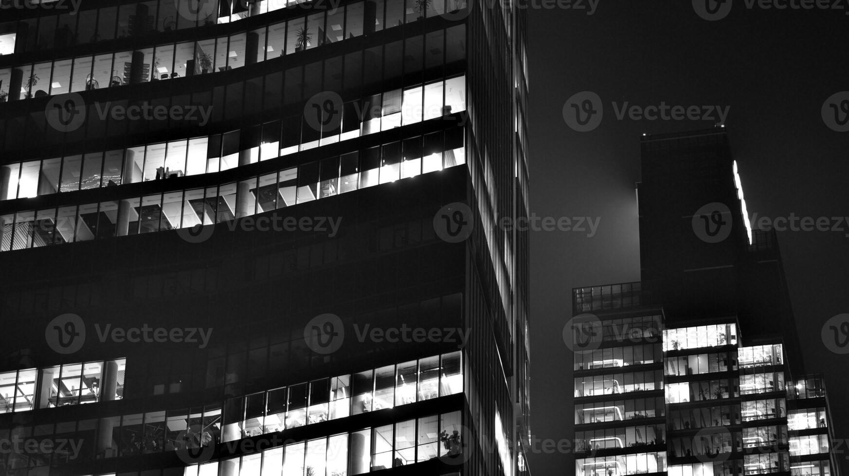 Pattern of office buildings windows illuminated at night. Glass architecture ,corporate building at night - business concept. Black and white. photo