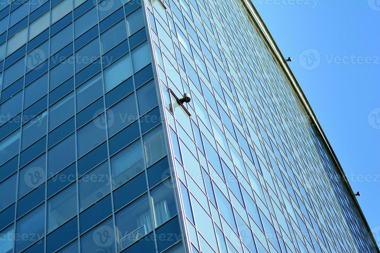 Glass building with transparent facade of the building and blue sky. Structural glass wall reflecting blue sky. Abstract modern architecture fragment. Contemporary architectural background. photo