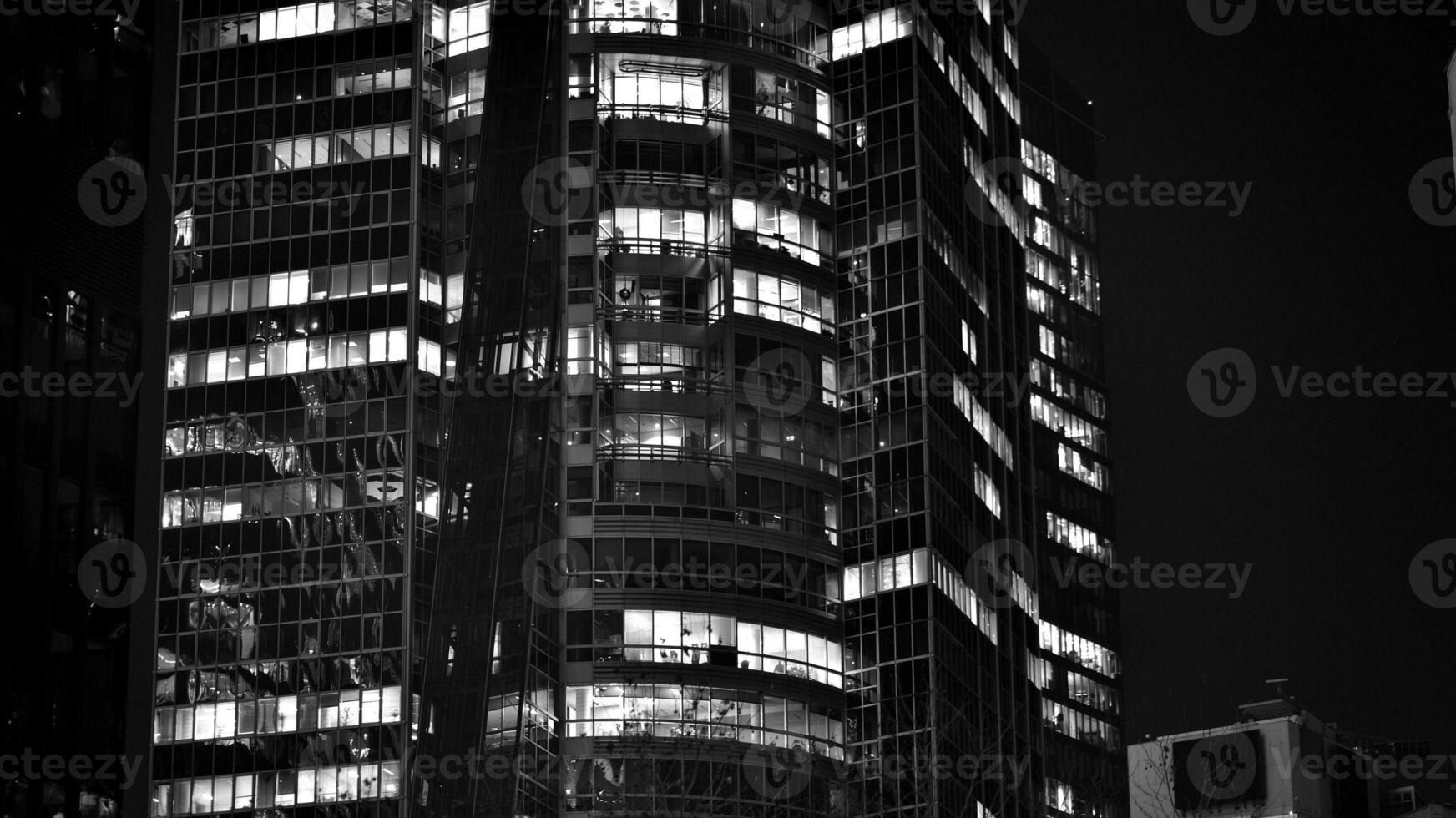 Pattern of office buildings windows illuminated at night. Glass architecture ,corporate building at night - business concept. Black and white. photo
