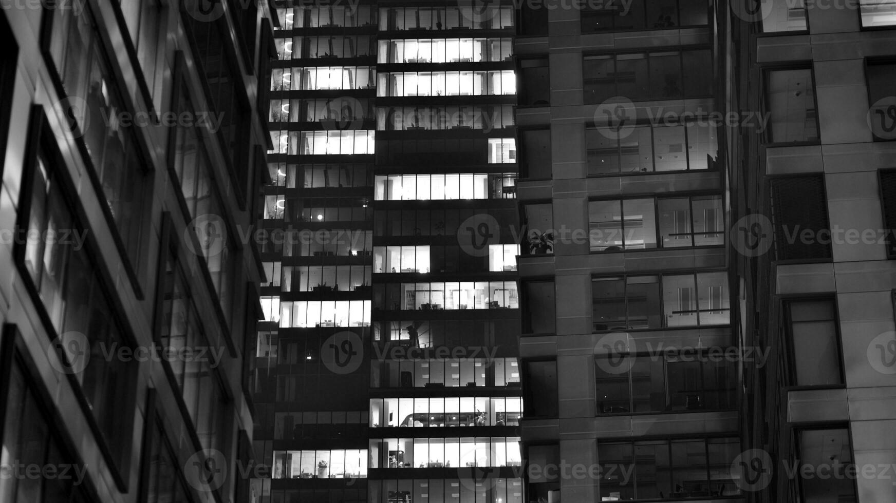 Pattern of office buildings windows illuminated at night. Glass architecture ,corporate building at night - business concept. Black and white. photo