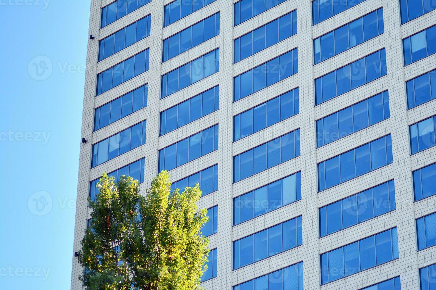 Glass building with transparent facade of the building and blue sky. Structural glass wall reflecting blue sky. Abstract modern architecture fragment. Contemporary architectural background. photo