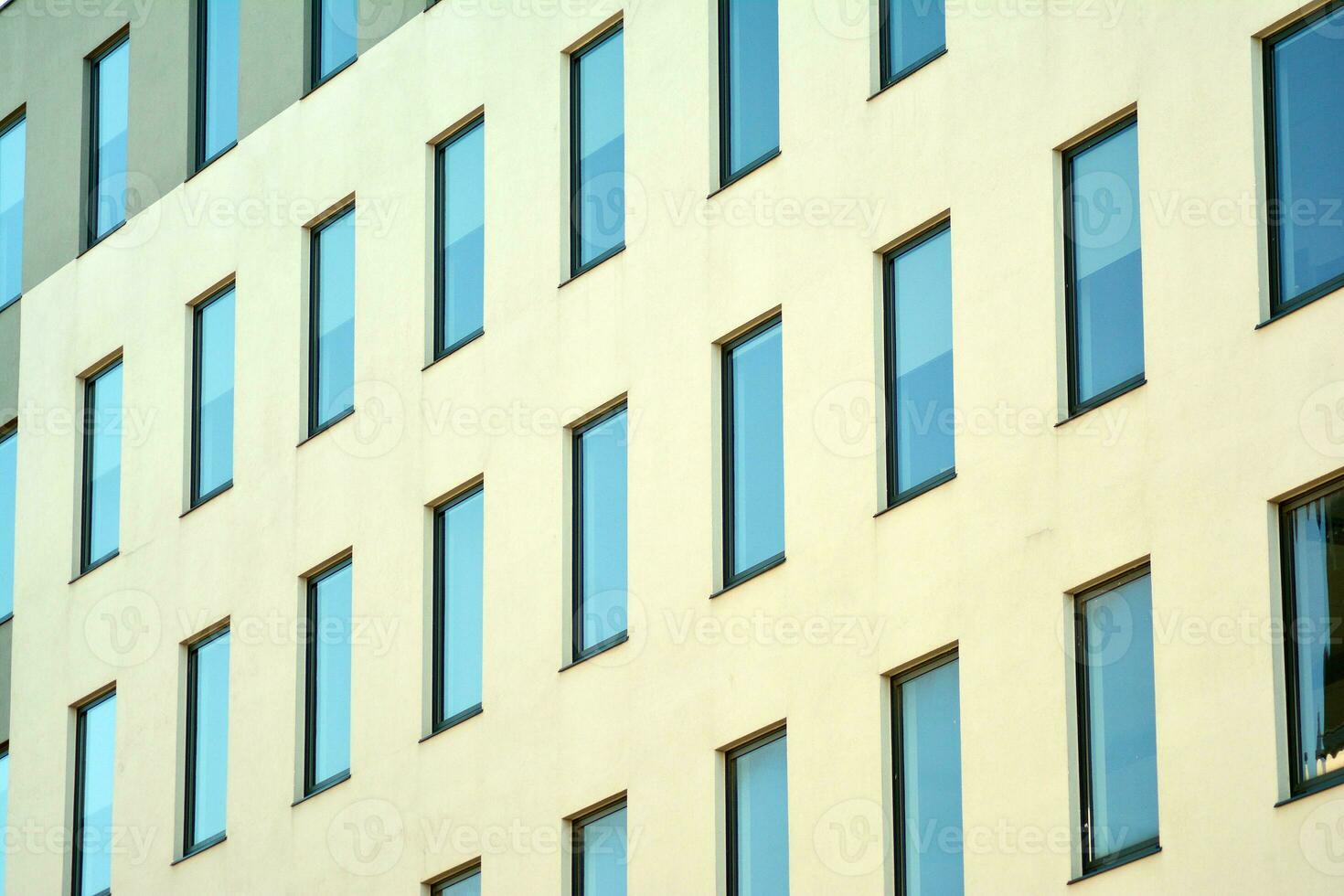 Abstract closeup of the glass-clad facade of a modern building covered in reflective plate glass. Architecture abstract background. Glass wall and facade detail. photo