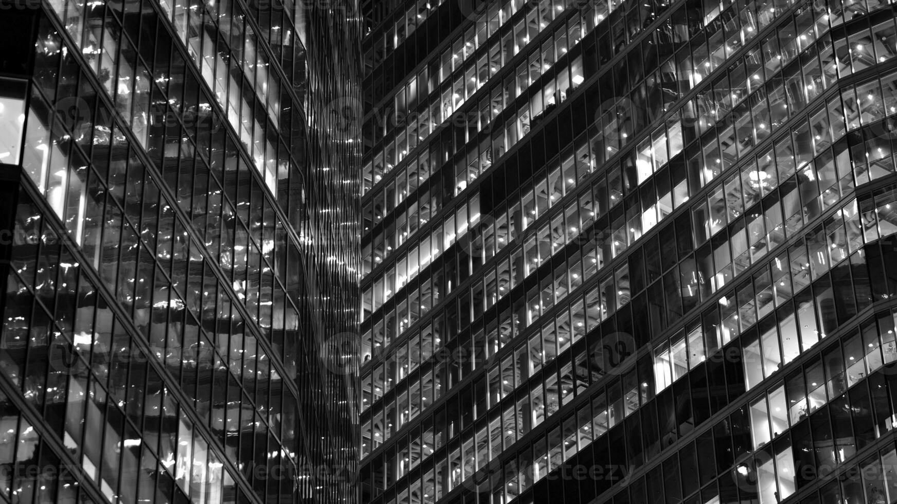 Pattern of office buildings windows illuminated at night. Glass architecture ,corporate building at night - business concept. Black and white. photo