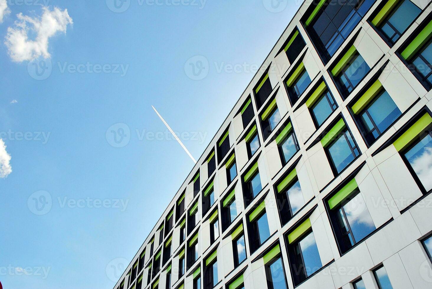 Abstract closeup of the glass-clad facade of a modern building covered in reflective plate glass. Architecture abstract background. Glass wall and facade detail. photo