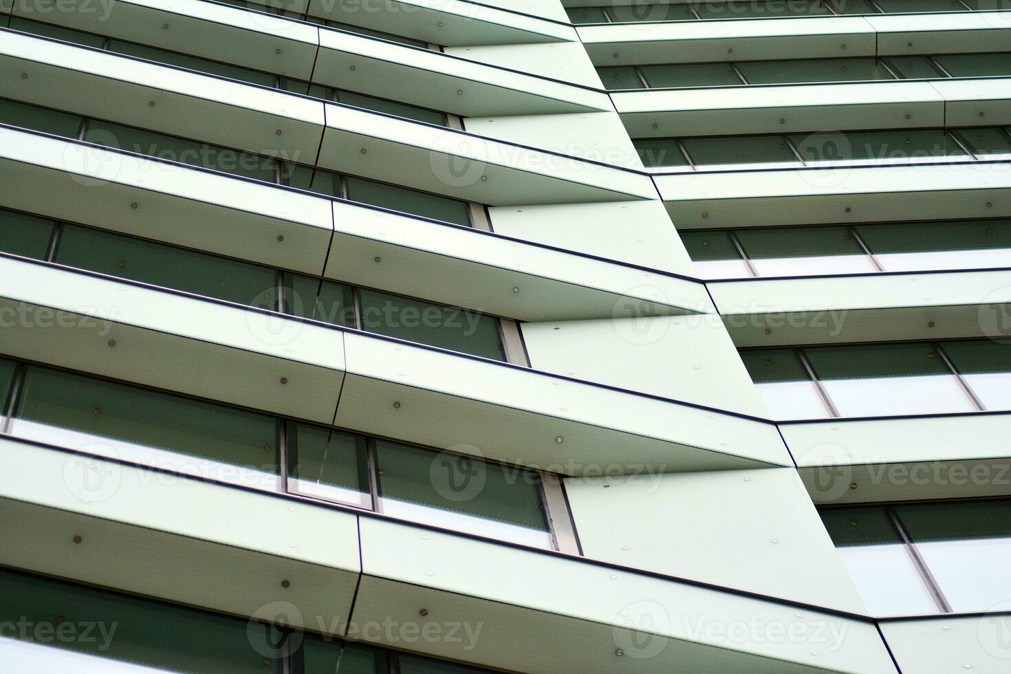 Abstract closeup of the glass-clad facade of a modern building covered in reflective plate glass. Architecture abstract background. Glass wall and facade detail. photo