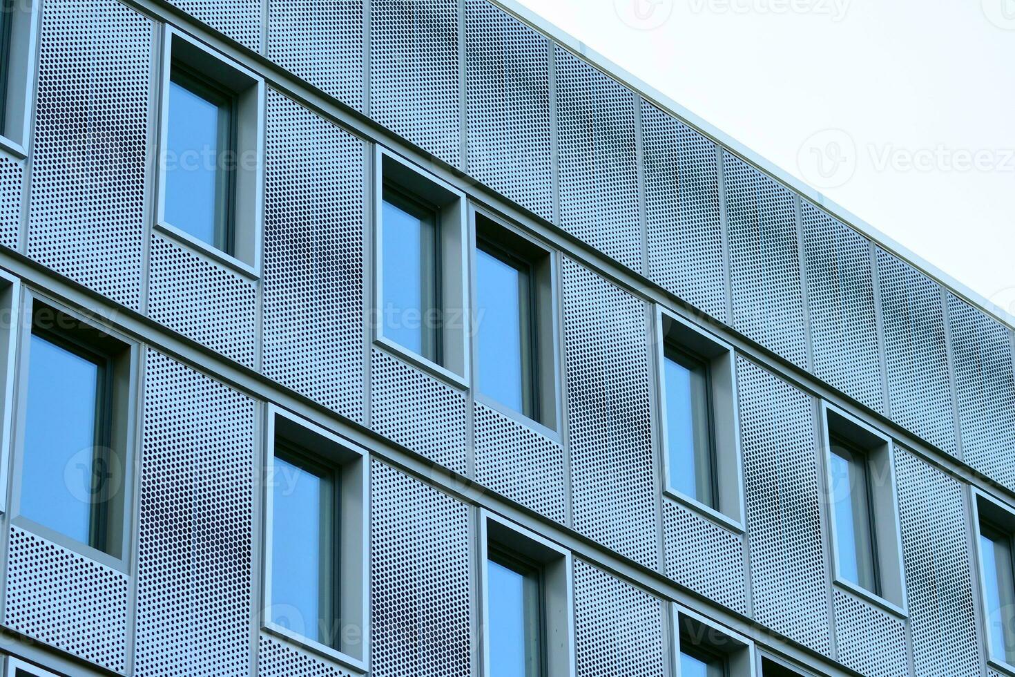 Abstract closeup of the glass-clad facade of a modern building covered in reflective plate glass. Architecture abstract background. Glass wall and facade detail. photo