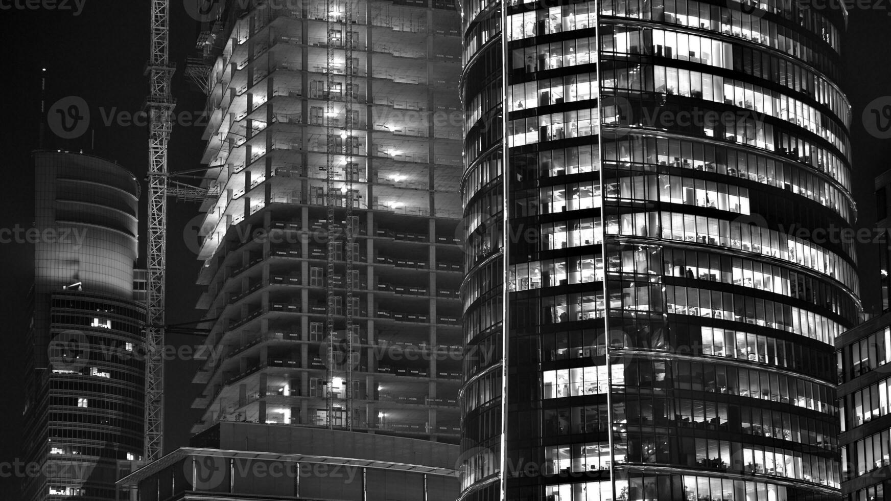 Pattern of office buildings windows illuminated at night. Glass architecture ,corporate building at night - business concept. Black and white. photo