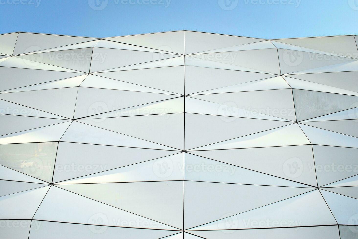 Abstract closeup of the glass-clad facade of a modern building covered in reflective plate glass. Architecture abstract background. Glass wall and facade detail. photo