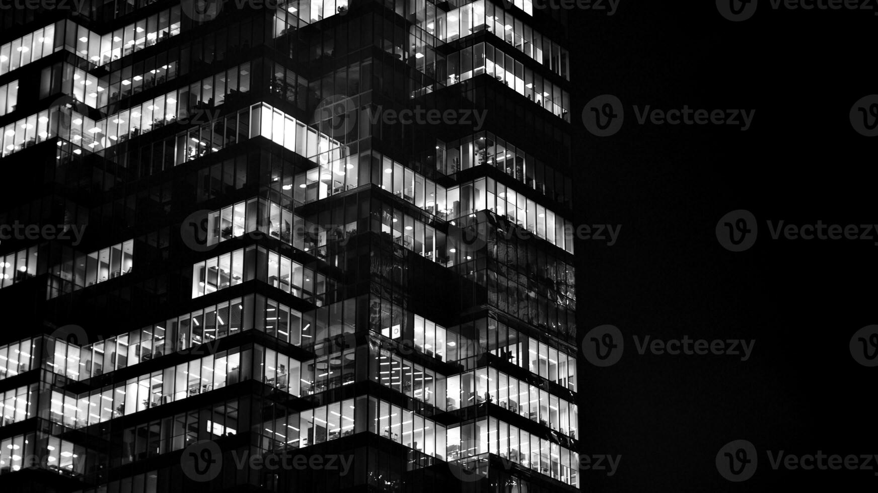 Pattern of office buildings windows illuminated at night. Glass architecture ,corporate building at night - business concept. Black and white. photo