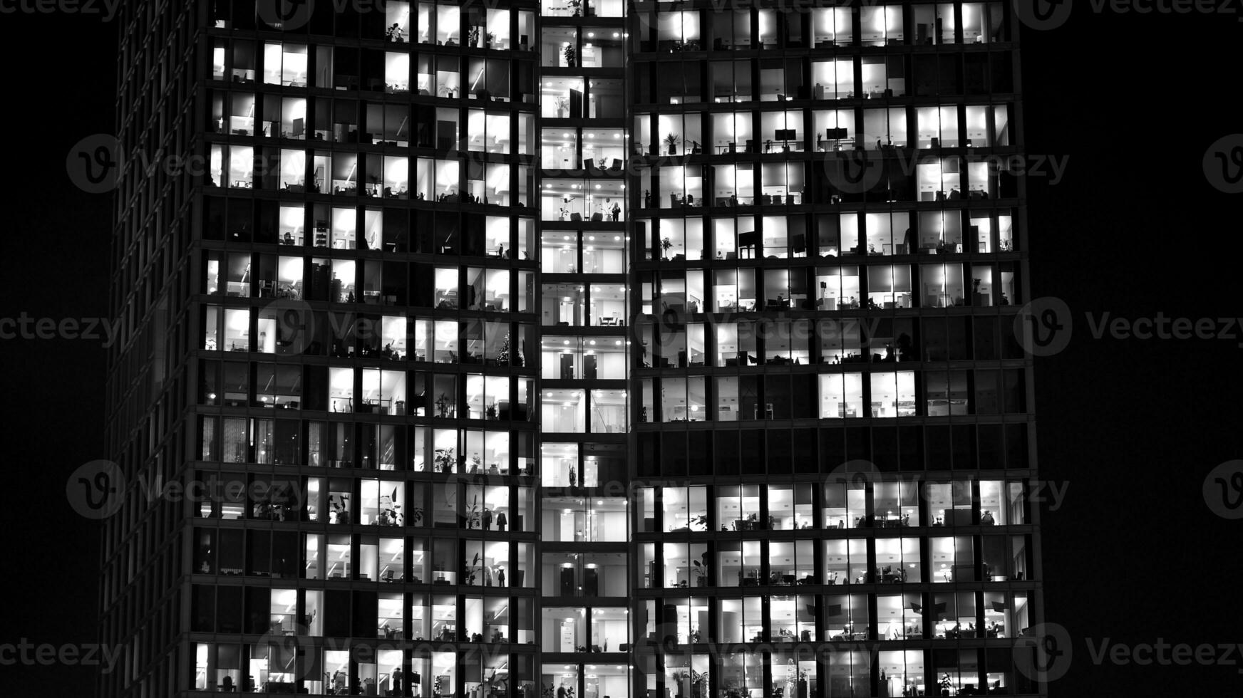 Pattern of office buildings windows illuminated at night. Glass architecture ,corporate building at night - business concept. Black and white. photo