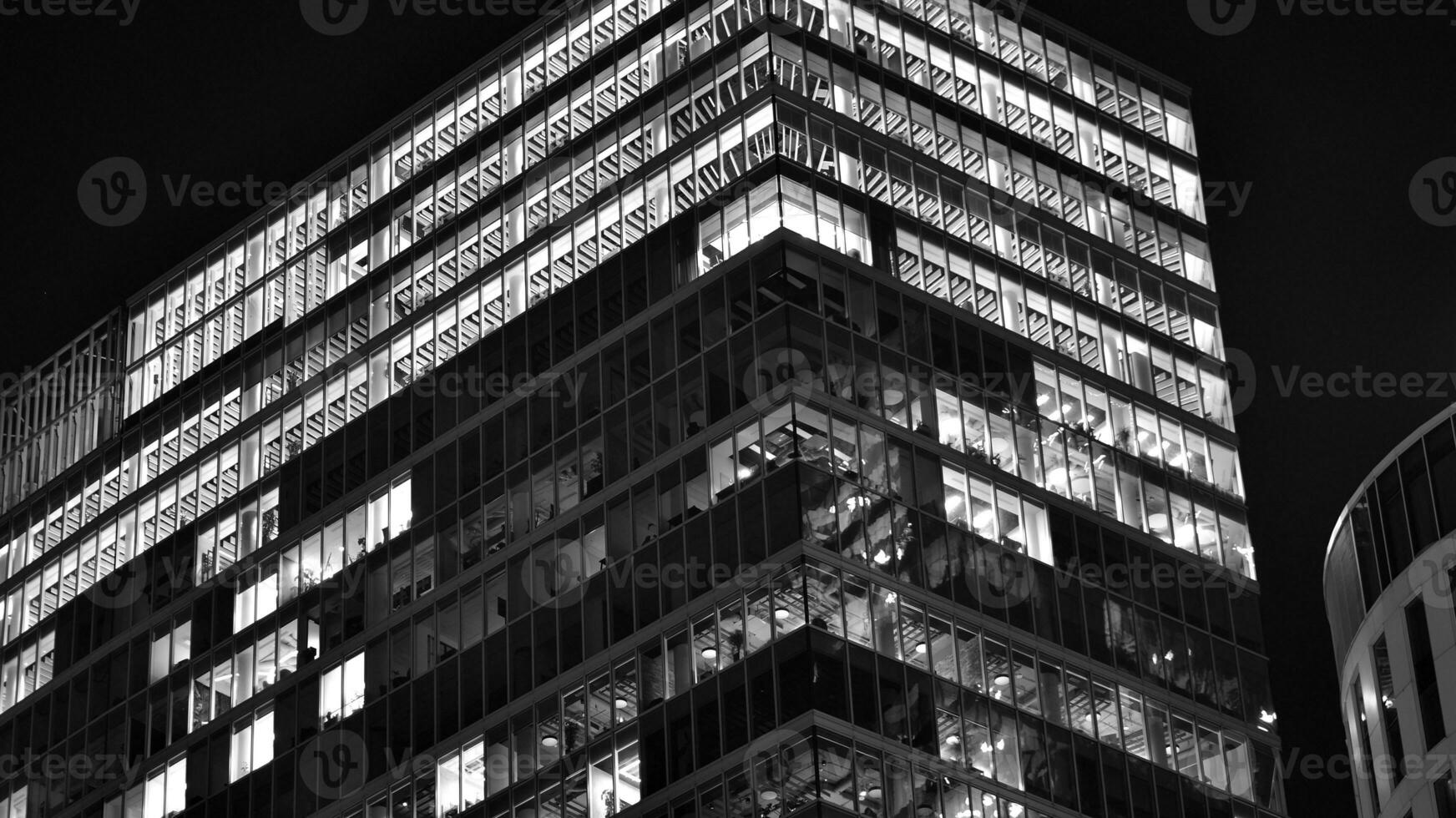 Pattern of office buildings windows illuminated at night. Glass architecture ,corporate building at night - business concept. Black and white. photo