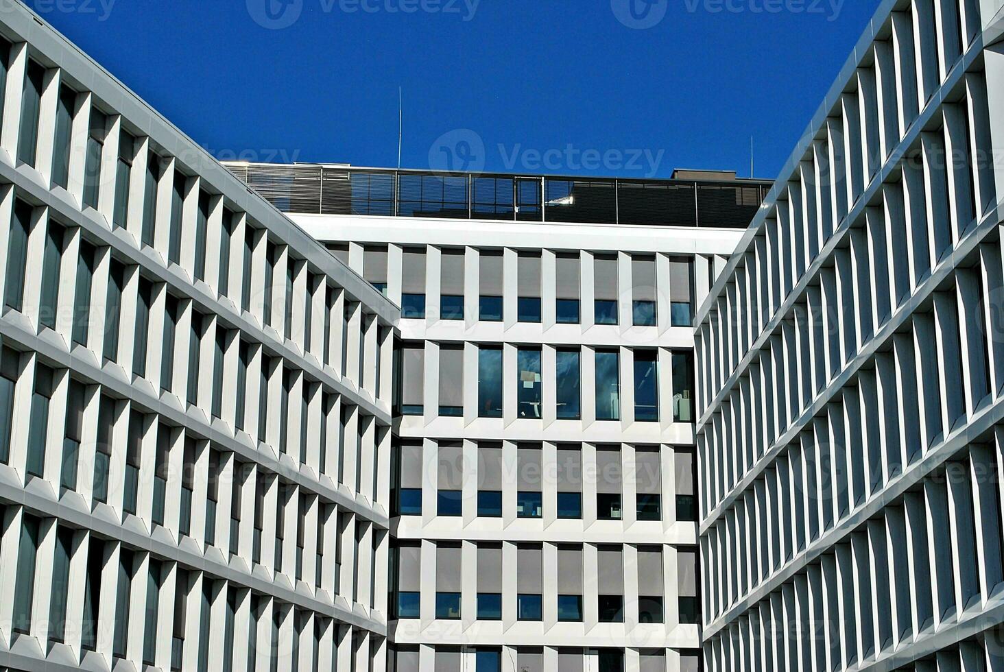 Abstract closeup of the glass-clad facade of a modern building covered in reflective plate glass. Architecture abstract background. Glass wall and facade detail. photo