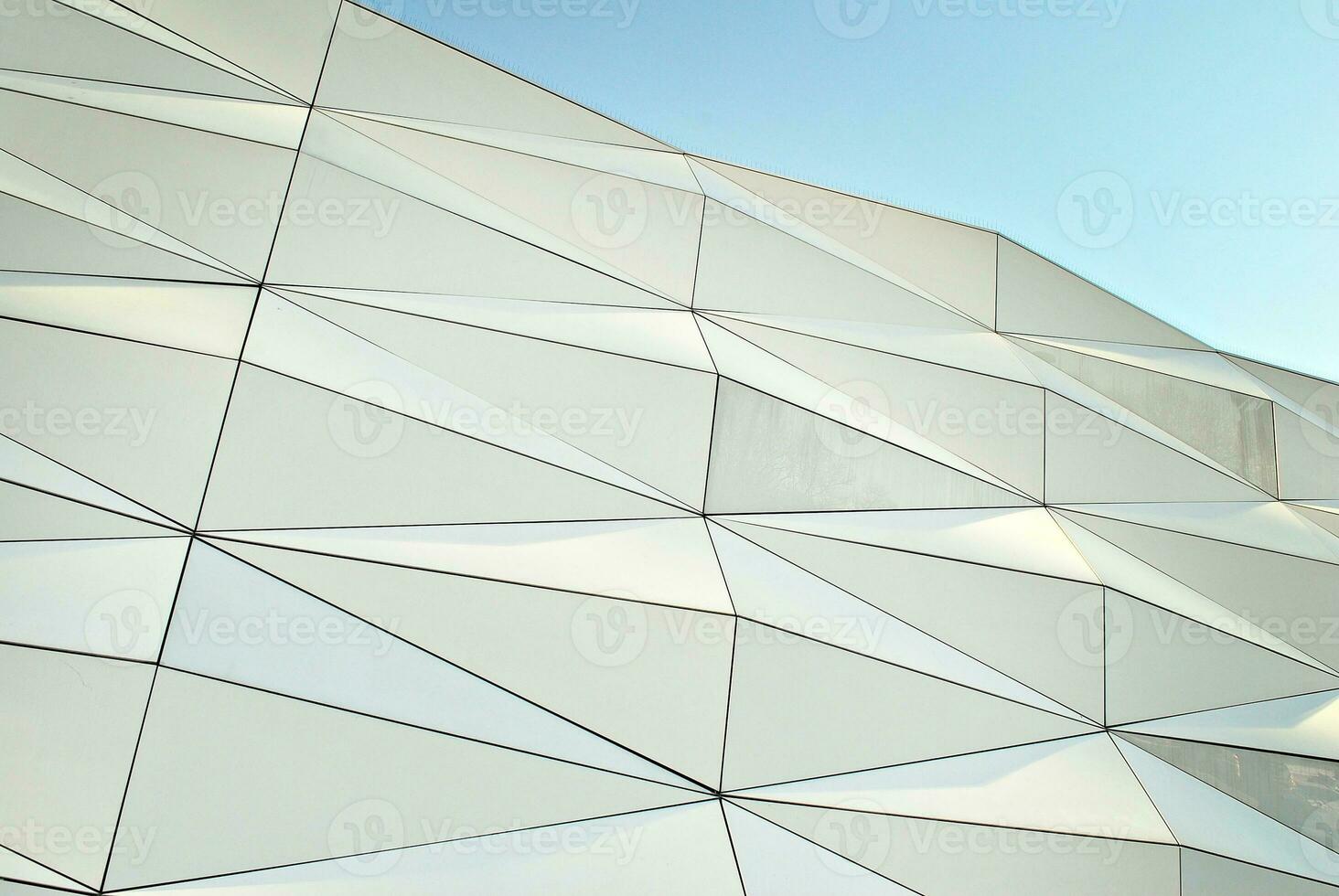 Abstract closeup of the glass-clad facade of a modern building covered in reflective plate glass. Architecture abstract background. Glass wall and facade detail. photo