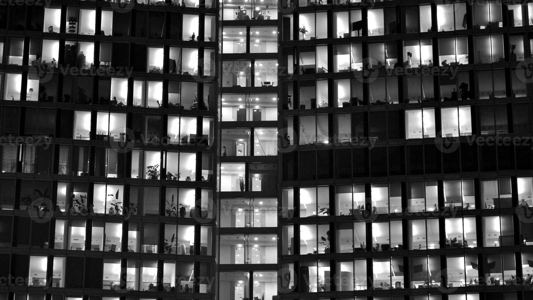 Pattern of office buildings windows illuminated at night. Glass architecture ,corporate building at night - business concept. Black and white. photo