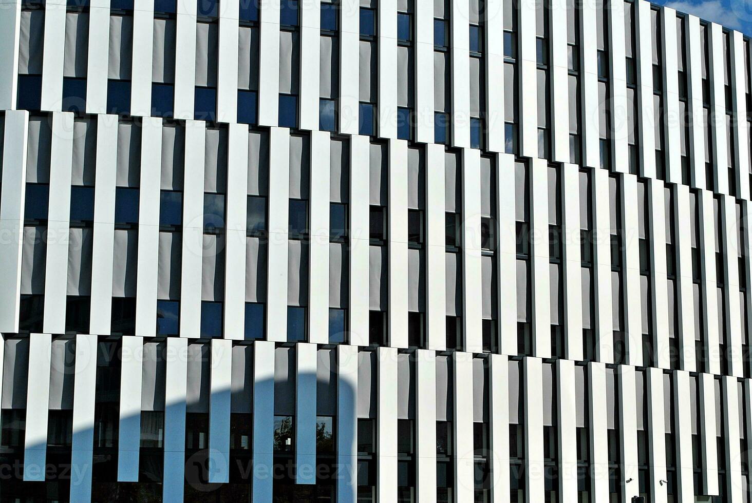 Abstract closeup of the glass-clad facade of a modern building covered in reflective plate glass. Architecture abstract background. Glass wall and facade detail. photo