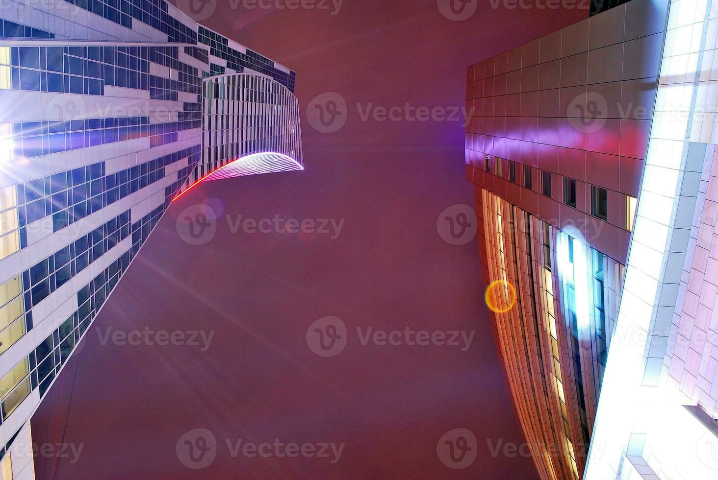 Fragment of the glass facade of a modern corporate building at night. Modern glass office  in city. Big glowing windows in modern office buildings at night, in rows of windows light shines. photo
