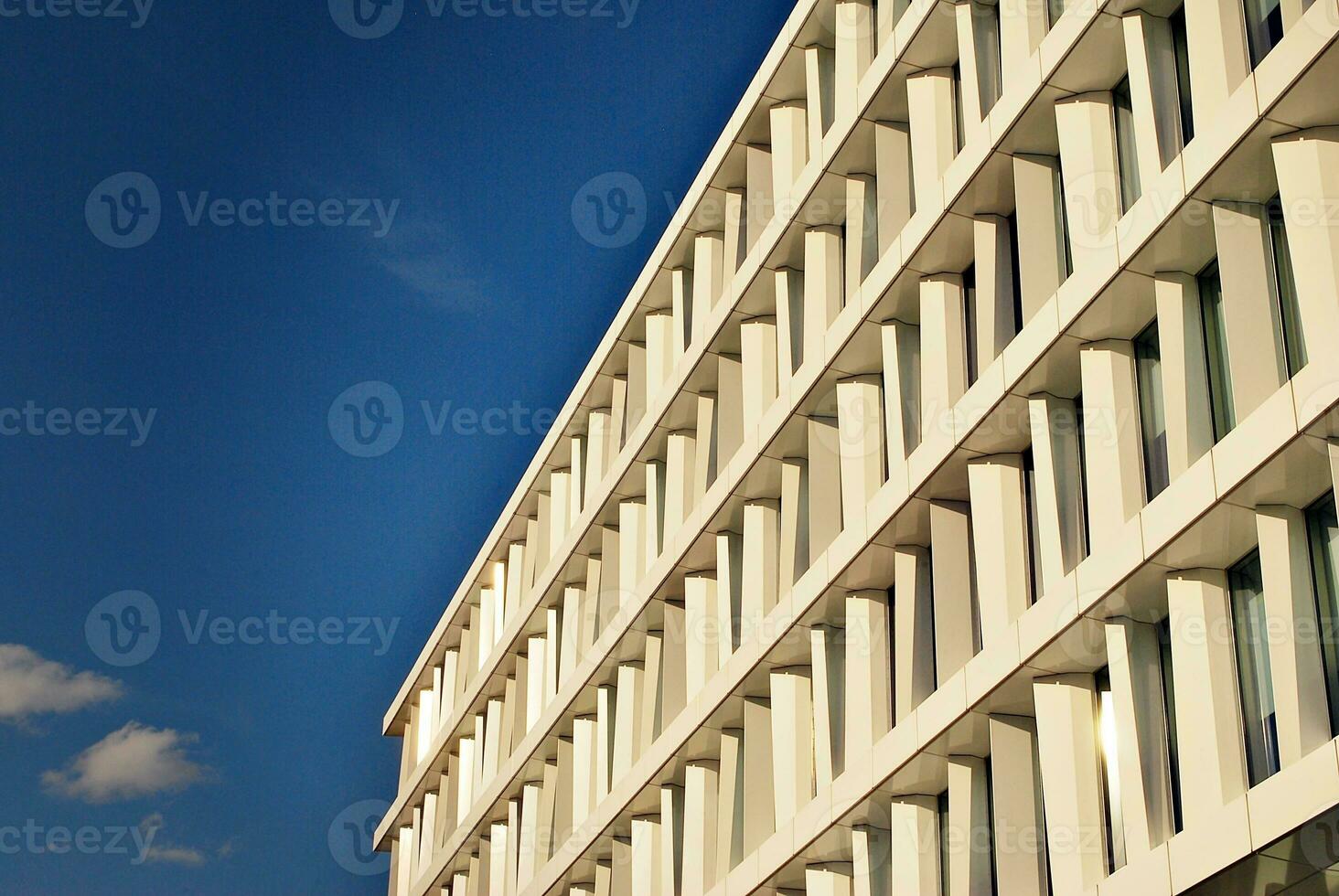 Abstract closeup of the glass-clad facade of a modern building covered in reflective plate glass. Architecture abstract background. Glass wall and facade detail. photo