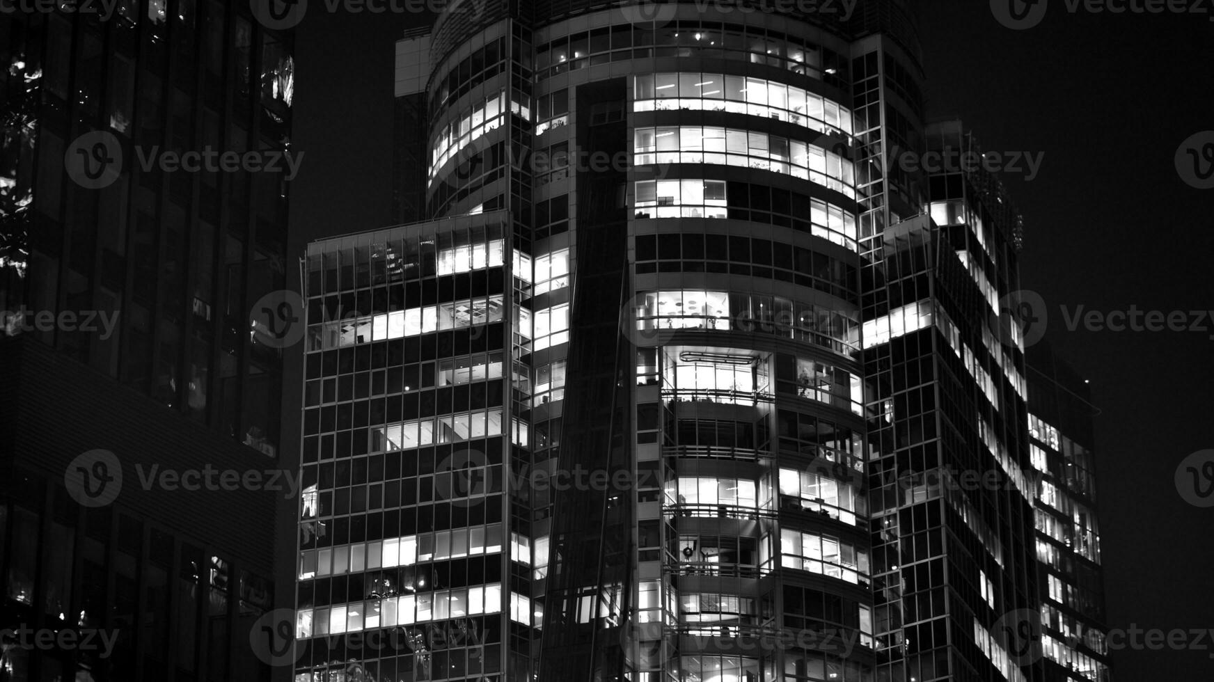 Pattern of office buildings windows illuminated at night. Glass architecture ,corporate building at night - business concept. Black and white. photo