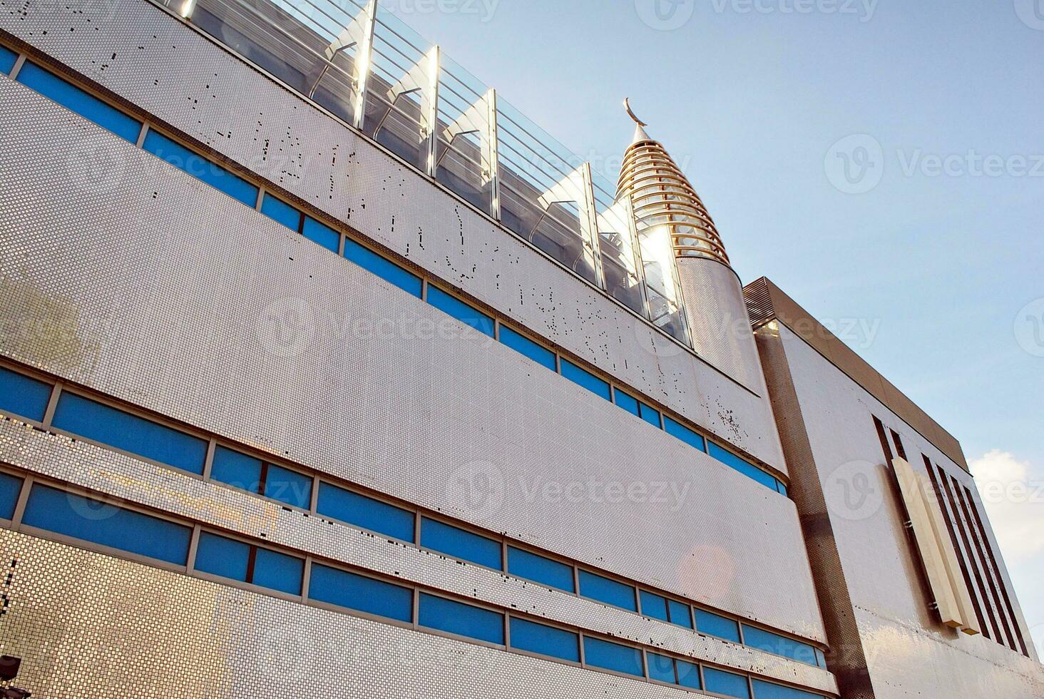 Abstract closeup of the glass-clad facade of a modern building covered in reflective plate glass. Architecture abstract background. Glass wall and facade detail. photo