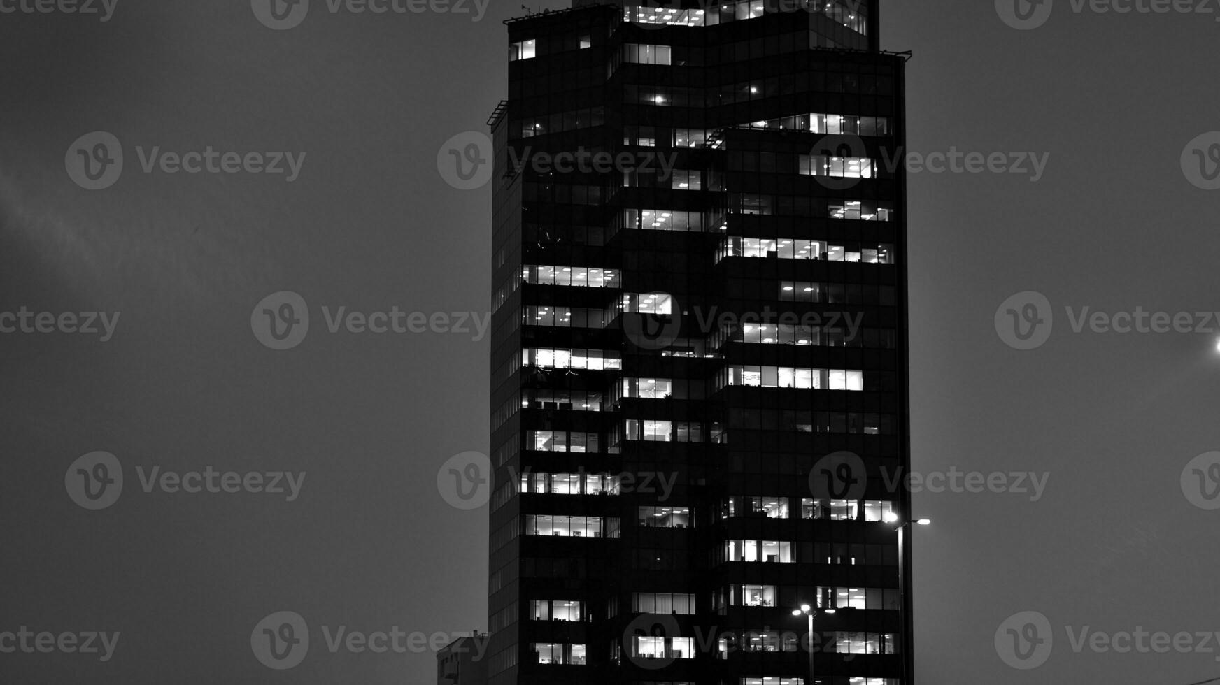 Pattern of office buildings windows illuminated at night. Glass architecture ,corporate building at night - business concept. Black and white. photo