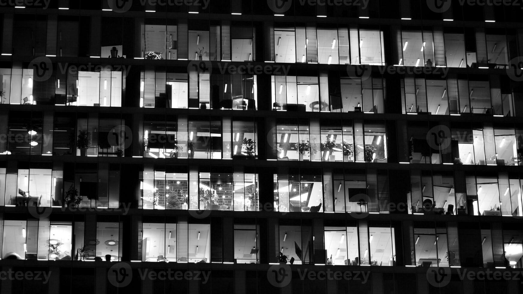 Pattern of office buildings windows illuminated at night. Glass architecture ,corporate building at night - business concept. Black and white. photo