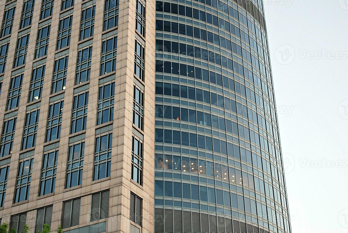 Abstract closeup of the glass-clad facade of a modern building covered in reflective plate glass. Architecture abstract background. Glass wall and facade detail. photo