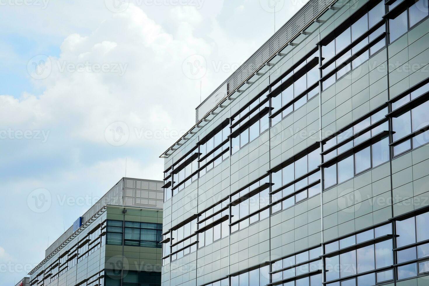 Abstract closeup of the glass-clad facade of a modern building covered in reflective plate glass. Architecture abstract background. Glass wall and facade detail. photo