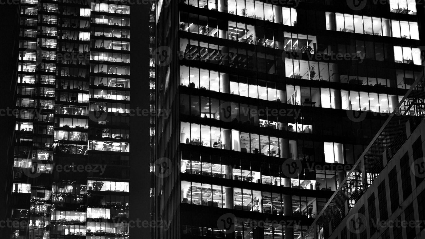 Pattern of office buildings windows illuminated at night. Glass architecture ,corporate building at night - business concept. Black and white. photo