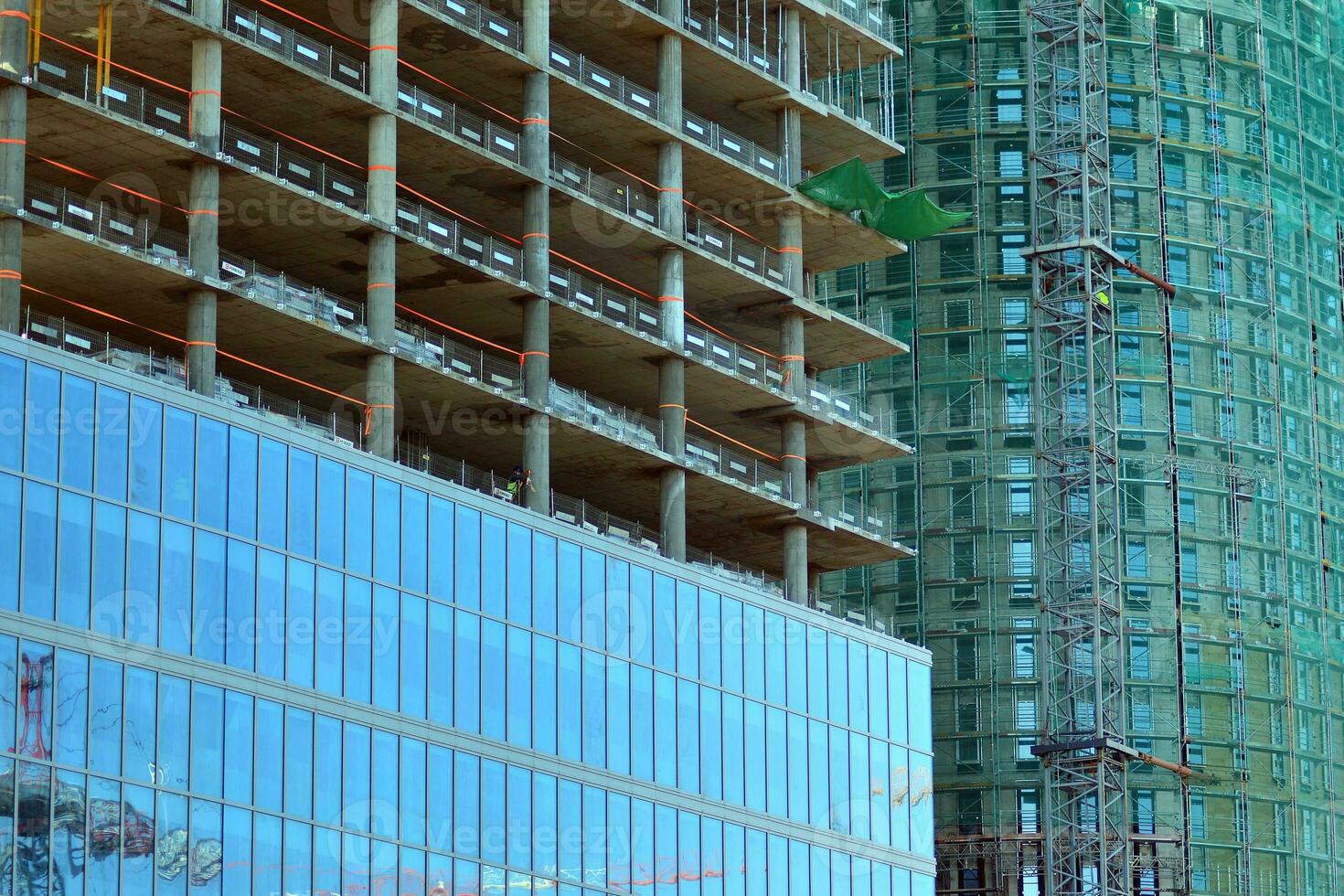 High rise building under construction. Installation of glass facade panels on a reinforced concrete structure. photo