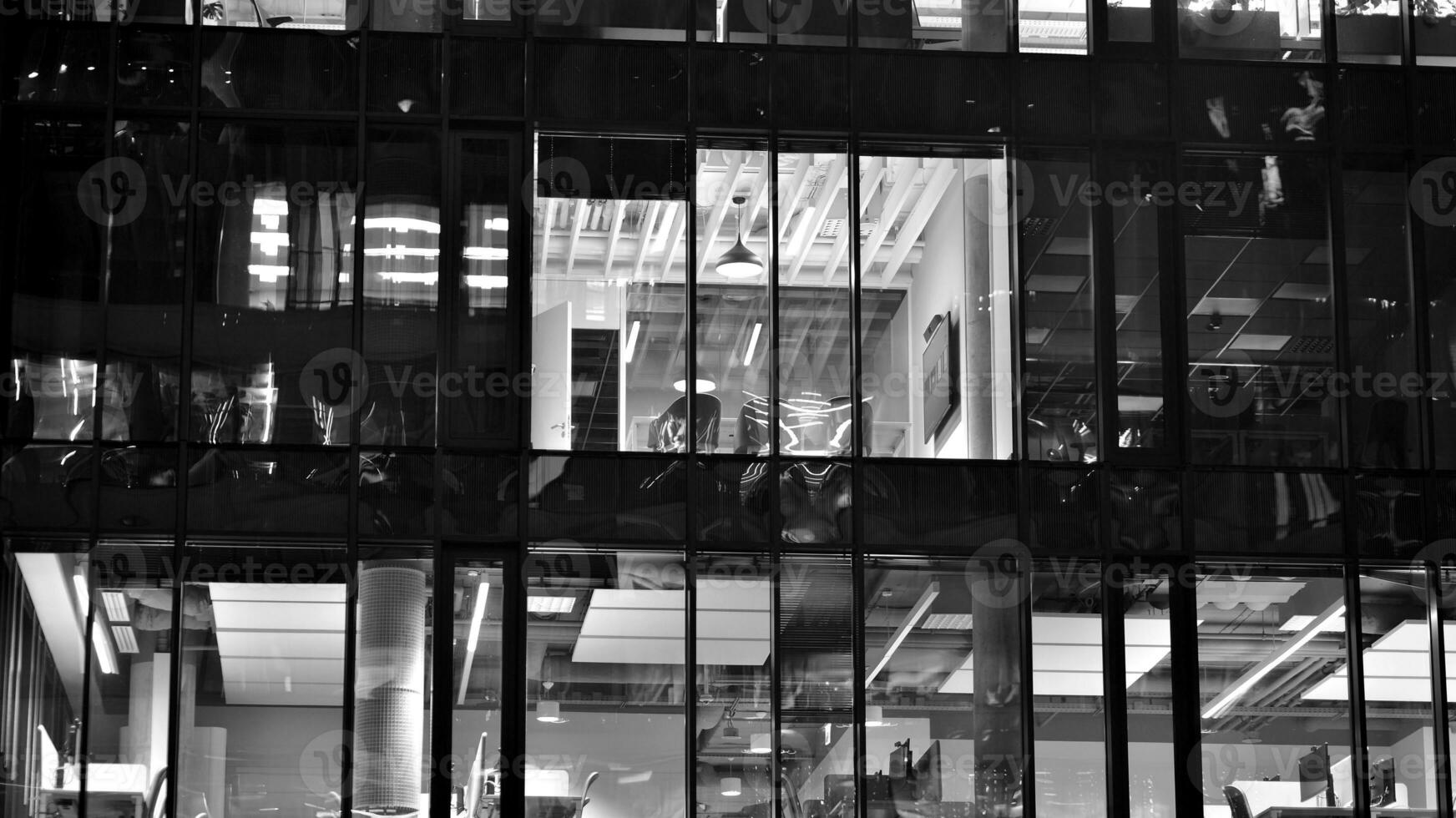 Pattern of office buildings windows illuminated at night. Glass architecture ,corporate building at night - business concept. Black and white. photo